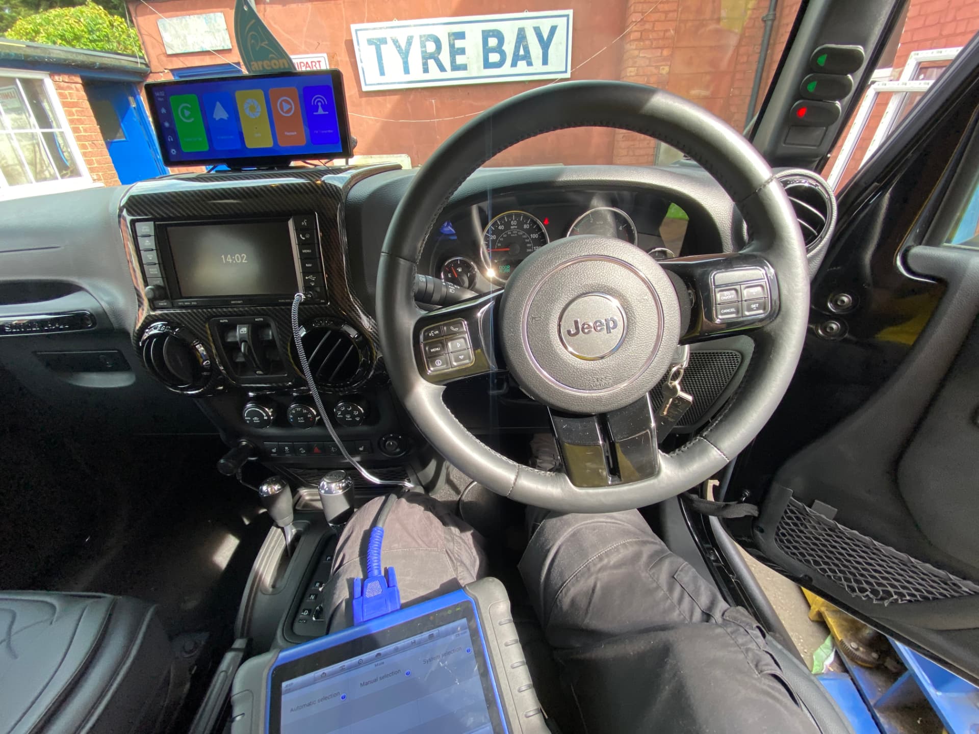 Auto locksmith sat in a Jeep cockpit with diagnostic key programming equipment connected