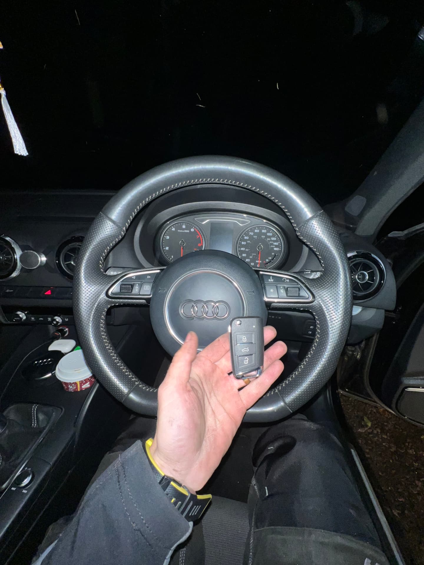 Audi flip key held in front of an Audi A3 steering wheel and instrument cluster